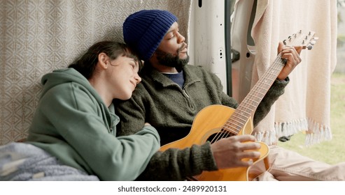 Interracial, couple and smile with guitar on campsite for honeymoon, holiday and adventure. People, love and happy with music instrument for bonding, support and care with trust on vacation or trip - Powered by Shutterstock