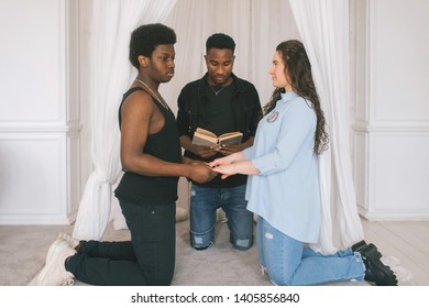 Interracial couple standing on knees in front of wedding arch. Interracial bridal ceremony. Caucasian woman getting married with african dark skinned boyfriend. Amateur wedding couple swear in love. - Powered by Shutterstock