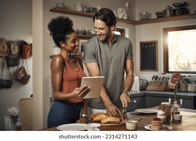 Interracial couple, tablet and cooking in kitchen for recipe, social media or online food vlog at home. Man and woman preparing breakfast meal or cutting ingredients together with technology on table - Powered by Shutterstock