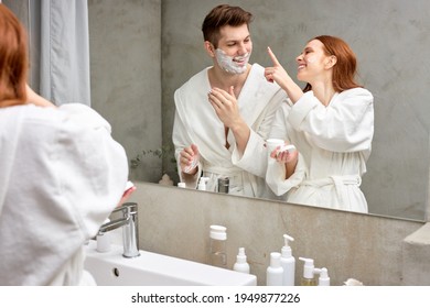 interracial couple take care of facial skin, woman applying cream while man is going to shave stubble - Powered by Shutterstock