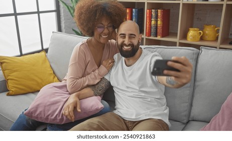 Interracial couple taking a selfie together on a cozy sofa in a modern living room - Powered by Shutterstock