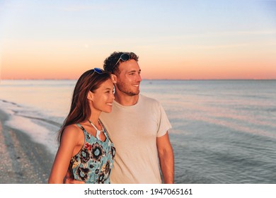 Interracial couple walking on Florida beach watching sunset. Young happy Asian woman and Caucasian man smiling natural beauty outdoor portrait. USA travel vacation. - Powered by Shutterstock