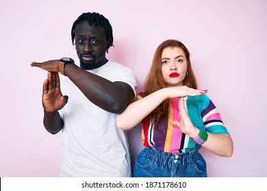 Interracial Couple Wearing Casual Clothes Doing Time Out Gesture With Hands, Frustrated And Serious Face 