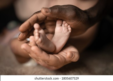 interethnische Familie, die Babyfüße in Händen hält, gemischt mit schwarz-weißer Hautfarbe