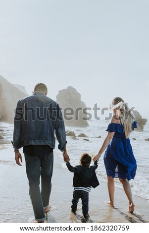 Interracial family walking along the beach in California text space