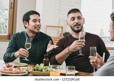 Interracial Gay Couple Having Party Drinking And Eating With Friend At Home