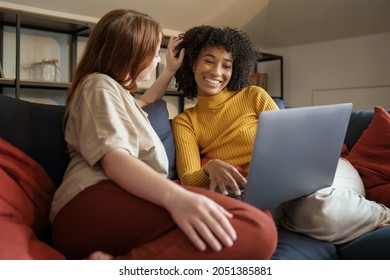 Interracial Gay Women Couple Using Laptop And Having Fun Sitting On The Couch