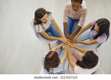 Interracial Group Of Five Happy Beautiful Young Multiethnic Women Sitting In A Circle And Holding Hands, An Overhead Top View High Angle Shot. Concept Of Team, Unity, Support And Helping Each Other