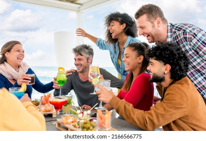 interracial group of friends at rooftop terrace bar at the beach having food and drinks celebrating happy hour on summer weekend. diverse people together enjoying holidays. fun and lifestyle concept - Powered by Shutterstock