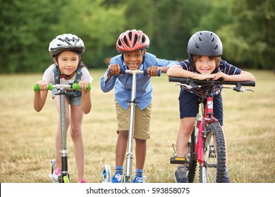 Interracial Group Of Kids With Bike And Scooter Smiling