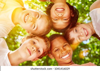 Interracial Group Of Kids Smiling And Putting Heads Together As Team