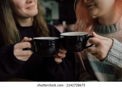 Interracial Lesbian Couple Each Other With Shy Smile, Holding Hands During Lunch At Restaurant. Happy Redhead Woman Confessing Love To Her Stylish Asian American Girlfriend With Pink Hair Hairstyle.