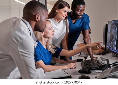 Interracial radiologists sitting at table in front of computer monitors with x-ray images and discussing diagnosis in team at office. medicine concept - Powered by Shutterstock