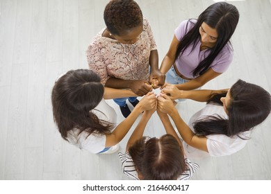 Interracial Team Of Five Happy Beautiful Young Multiethnic Women Standing In A Circle And Holding Hands, Overhead Top View High Angle Shot. Girl Power, Unity, Support Group, Helping Each Other Concept