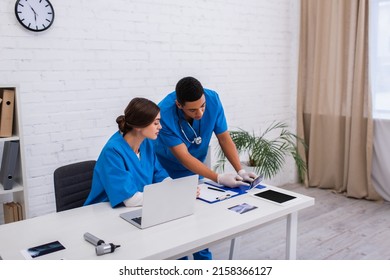 Interracial Vet Doctors Looking At Ultrasound Scan Near Devices In Clinic