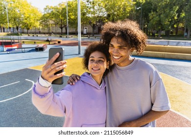 Interracial young couple dating outdoors, colored and modern urban background - Multiethnic people with stylish and cool urban clothes bonding outdoors