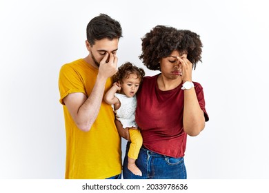 Interracial young family of black mother and hispanic father with daughter tired rubbing nose and eyes feeling fatigue and headache. stress and frustration concept. 