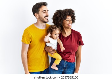 Interracial Young Family Of Black Mother And Hispanic Father With Daughter Looking Away To Side With Smile On Face, Natural Expression. Laughing Confident. 