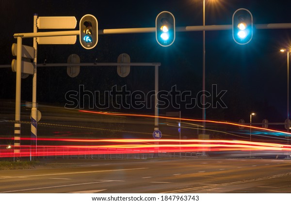 Intersection at night with traffic\
lights and traffic blurred by motion in Arnhem,\
Netherlands