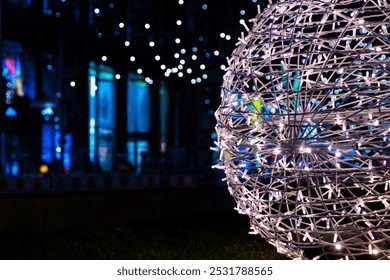 Intertwined white sliver string lights on the street next to Christmas market.. Crisscrossing glowing LED garland with small bright bulbs against dark background. Berlin, Germany. Copy space