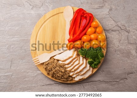 Interval fasting diet concept represented with a plate and products on dark stone table. Weight loss concept. Healthy breakfast with vegetables, turkey breast, quinoa.