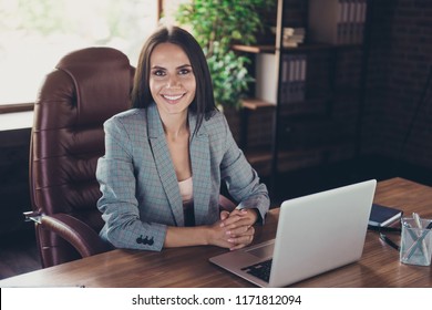 Interview for a new position concept. Successful stylish brunette lady in a gray checkered jacket sit behind the desk in comfort workplace