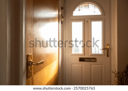Interview view of a hallway seen from the front door of a modern detached home. The door on the left leads to a ground floor shower room.