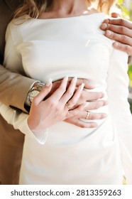 An intimate concept of love and commitment featuring a newlywed couple embracing, showcasing classic gold wedding rings and elegant bridal style.