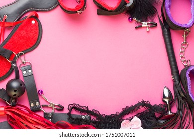 Intimate games. BDSM sex tools dildo vibrator, female panties, gag, nipple clamps, handcuffs, blindfold, buttplug and other on red pink background. Free space for your text.