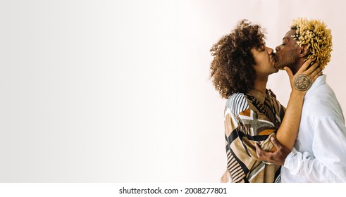 Intimate Gay Couple Kissing Passionately. Two Young Male Lovers Sharing An Affectionate Moment While Embracing Each Other. Young Gay Couple Standing Together Against A Studio Background.