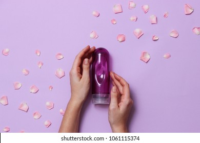 an intimate grease on a pastel background in female hands and rose petals. intimate massage. comfortable sex.