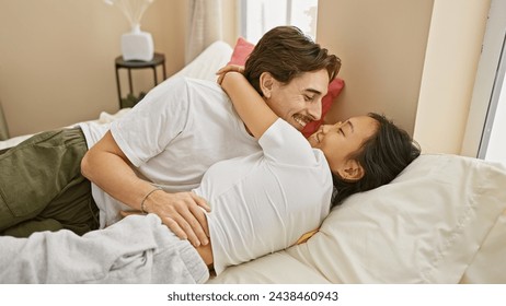 Intimate interracial couple embracing lovingly on a cozy bedroom bed, evoking romance and togetherness in a home setting. - Powered by Shutterstock