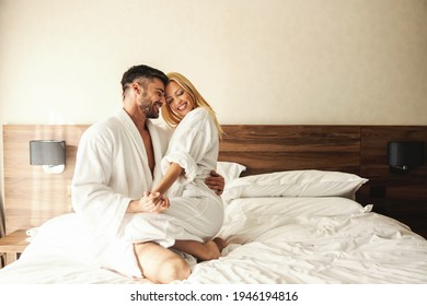 Intimate moments full of love and passion to remember. Happy couple laughing during a holiday stay in a hotel room. Beautiful blonde sitting on her beloved husband's lap, honeymoon, Valentine's Day