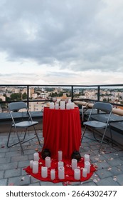 An intimate rooftop dining setup for two with a red tablecloth, flickering candles, and a stunning city skyline view, evoking a romantic evening atmosphere