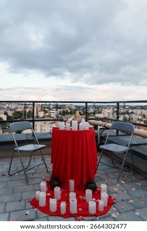 An intimate rooftop dining setup for two with a red tablecloth, flickering candles, and a stunning city skyline view, evoking a romantic evening atmosphere
