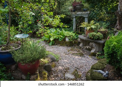 An Intimate Shaded Backyard Retreat Filled With Plants, Pots, And Stone Accessories.