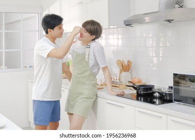 Intimate Young LGBT Asian Gay Couple Happy And Having Romantic Moment Together In The Kitchen During Cooking On Holiday.