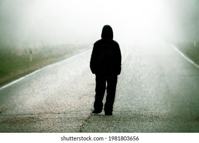 Into The Dim Outlook (vague Future) Concept. The Figure Of A Man Walking On A Foggy Road, Daze Fogscape. The Person Is Not Identified