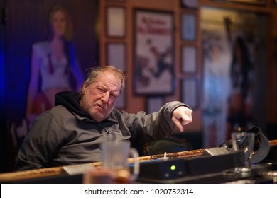 Intoxicated Man At The Bar Pointing At His Drink For The Bartender To Refill His Cup