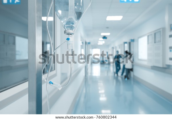 病院の廊下で話している看護師の背景にラックに点滴 の写真素材 今すぐ編集