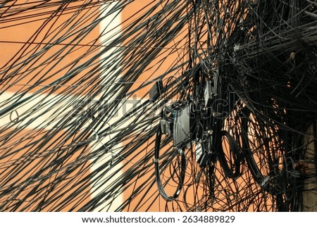 An intricate arrangement of tangled electrical wires showcases the complexity of urban infrastructure, highlighting the chaos and connectivity of modern technology.