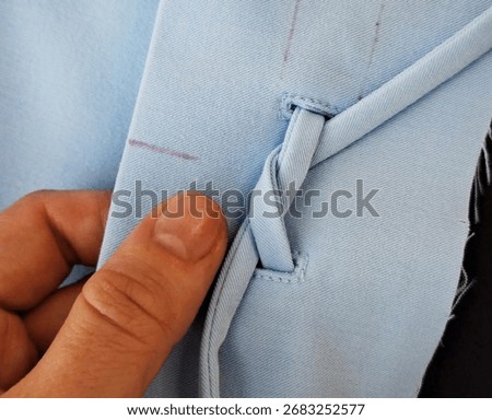 Intricate blue fabric loop skillfully fashioned, hand touch reveals hidden craft tales, Textile Day harmony, niche sartorial art