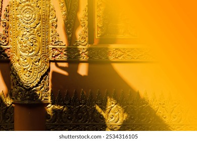 Intricate golden carvings on a temple wall, radiating warmth as sunlight casts dramatic shadows, blending with soft orange hues. - Powered by Shutterstock