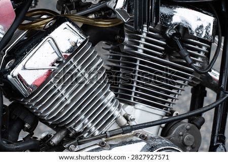 Intricate view of motorcycle engine assembly with emphasis on metallic textures, reflective chrome, and aluminum cooling fins, displaying a blend of robust construction and precise engineering, captured with visible water droplets