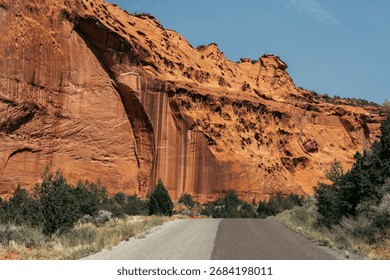 Intriguing path lined by towering orange cliffs under a clear blue sky.