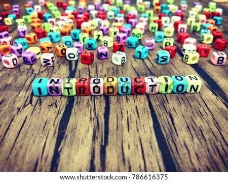 INTRODUCTION word of colourful cube alphabet on wooden table.