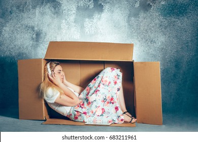 Introvert concept. Woman sitting inside box and working with laptop