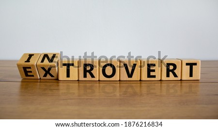 Introvert or extrovert symbol. Fliped cubes and changed the word 'introvert' to 'extrovert'. Beautiful wooden table, white background, copy space. Psychological and Introvert or extrovert concept.