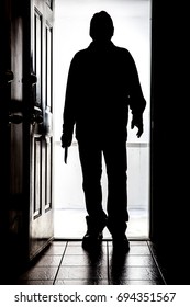 Intruder Standing At Doorway Threshold, In Silhouette With Buck Knife