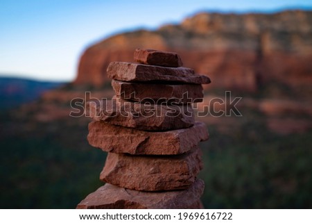 Inukshuk rock stack and trail marker with red butte cliff in the background near Devils Bridge in Sedona, Arizona.